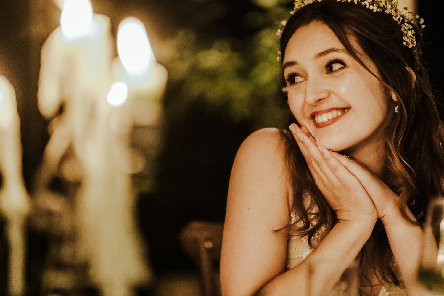 A joyful bride in an evening setting with glowing bokeh lights in the background.