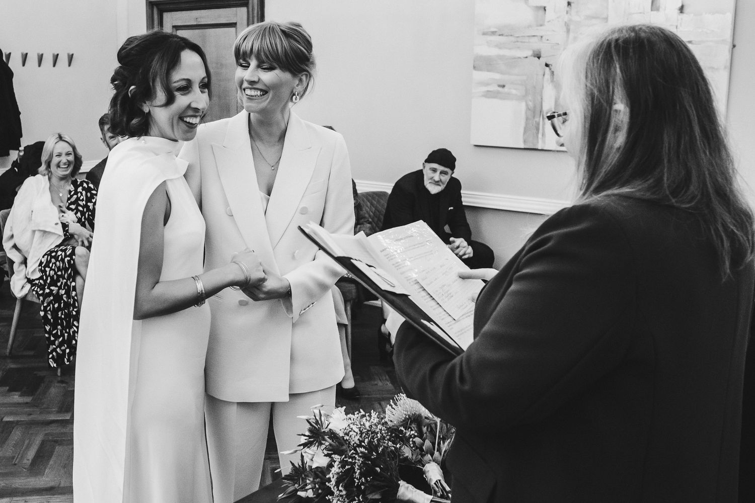 Black and white photo of a wedding ceremony with couple signing documents.