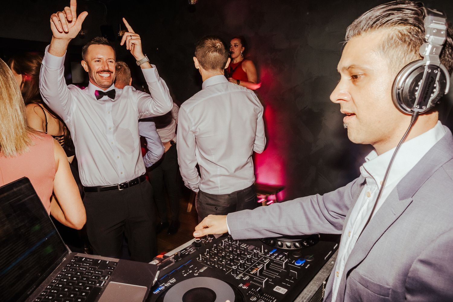 Wedding reception dance floor with guests dancing under dramatic lighting.