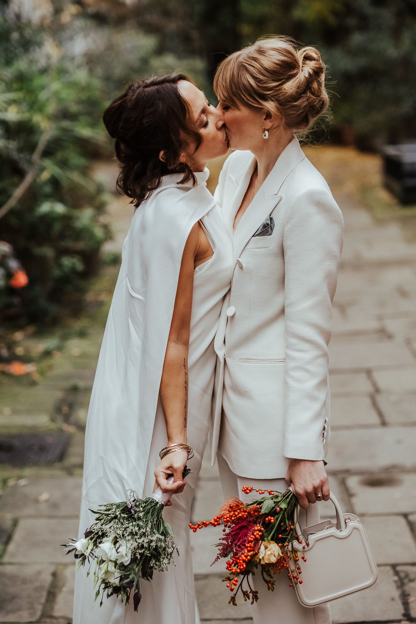 A romantic wedding moment captured on a stone pathway surrounded by garden greenery.