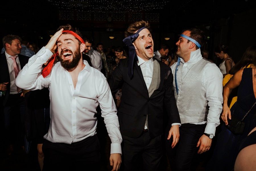 Three wedding guests singing and dancing enthusiastically at a reception party.