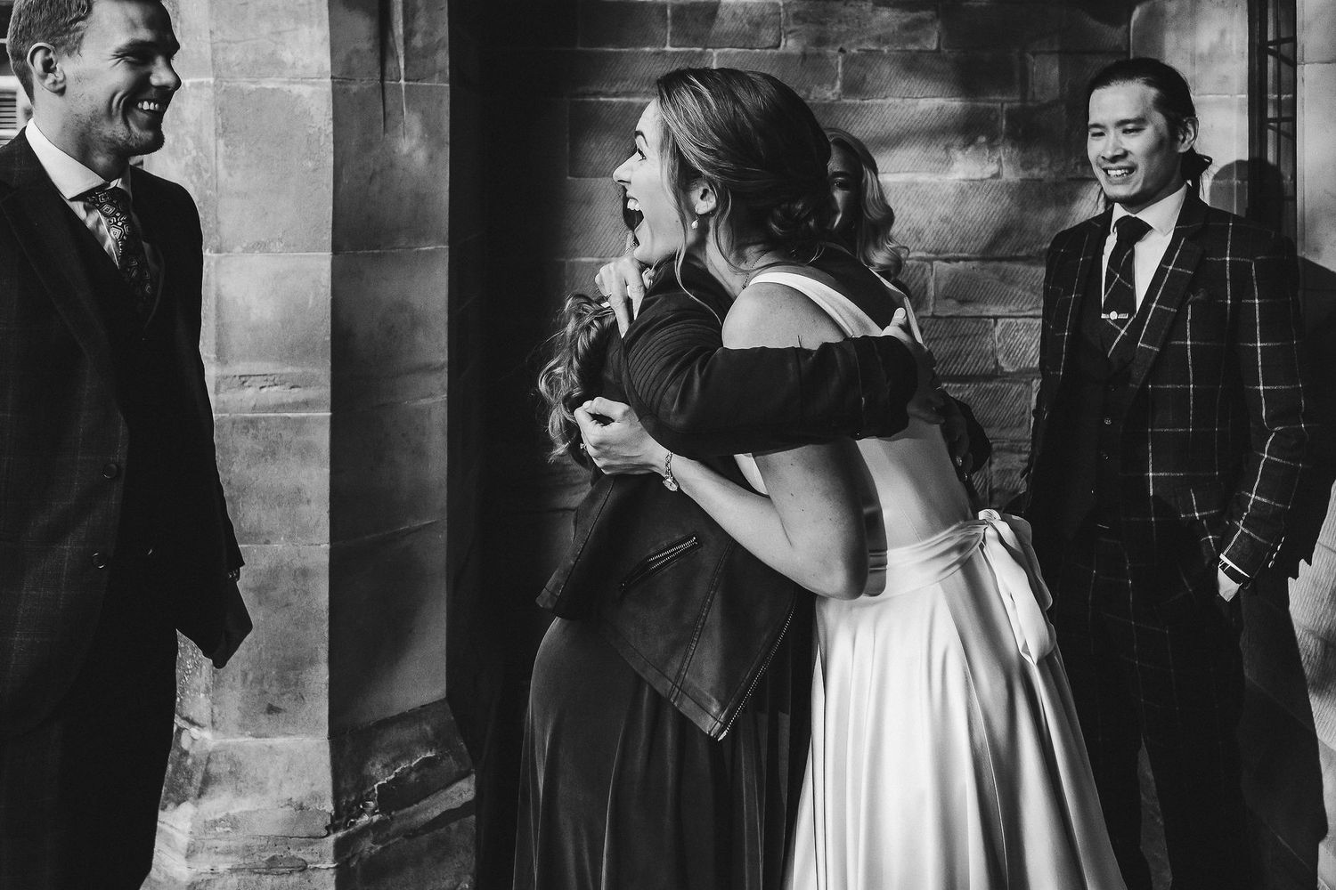 Elegant black and white wedding photography capturing intimate moments against brick wall backdrop.