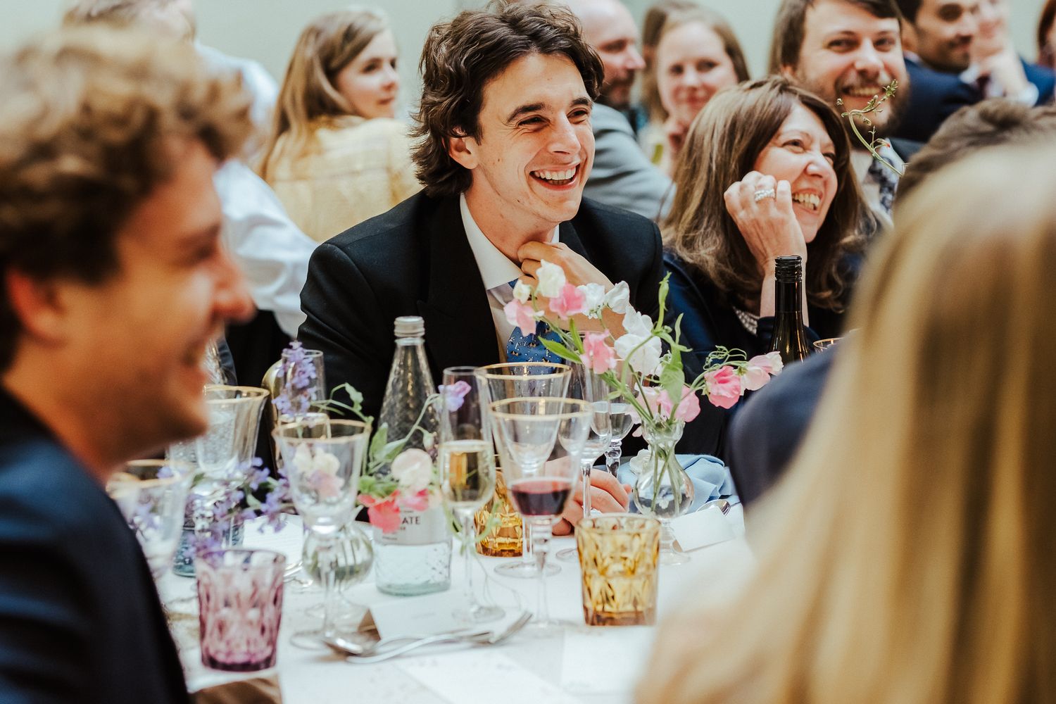 Candid moments of laughter and celebration captured at a wedding reception dinner.