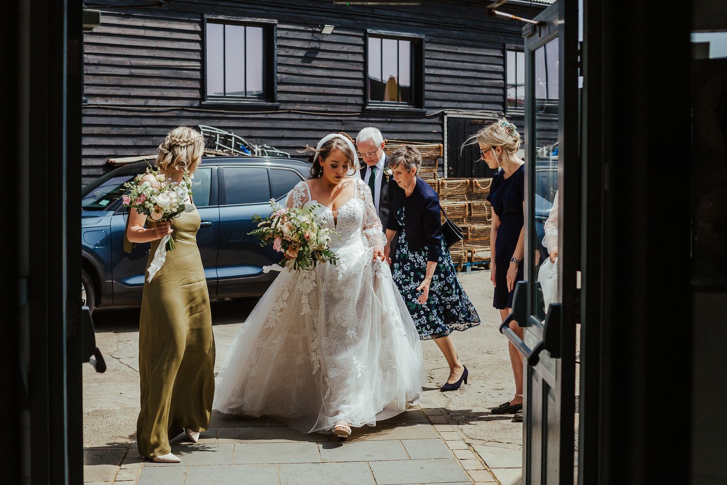 Wedding party gathered outside a rustic black building on the big day.