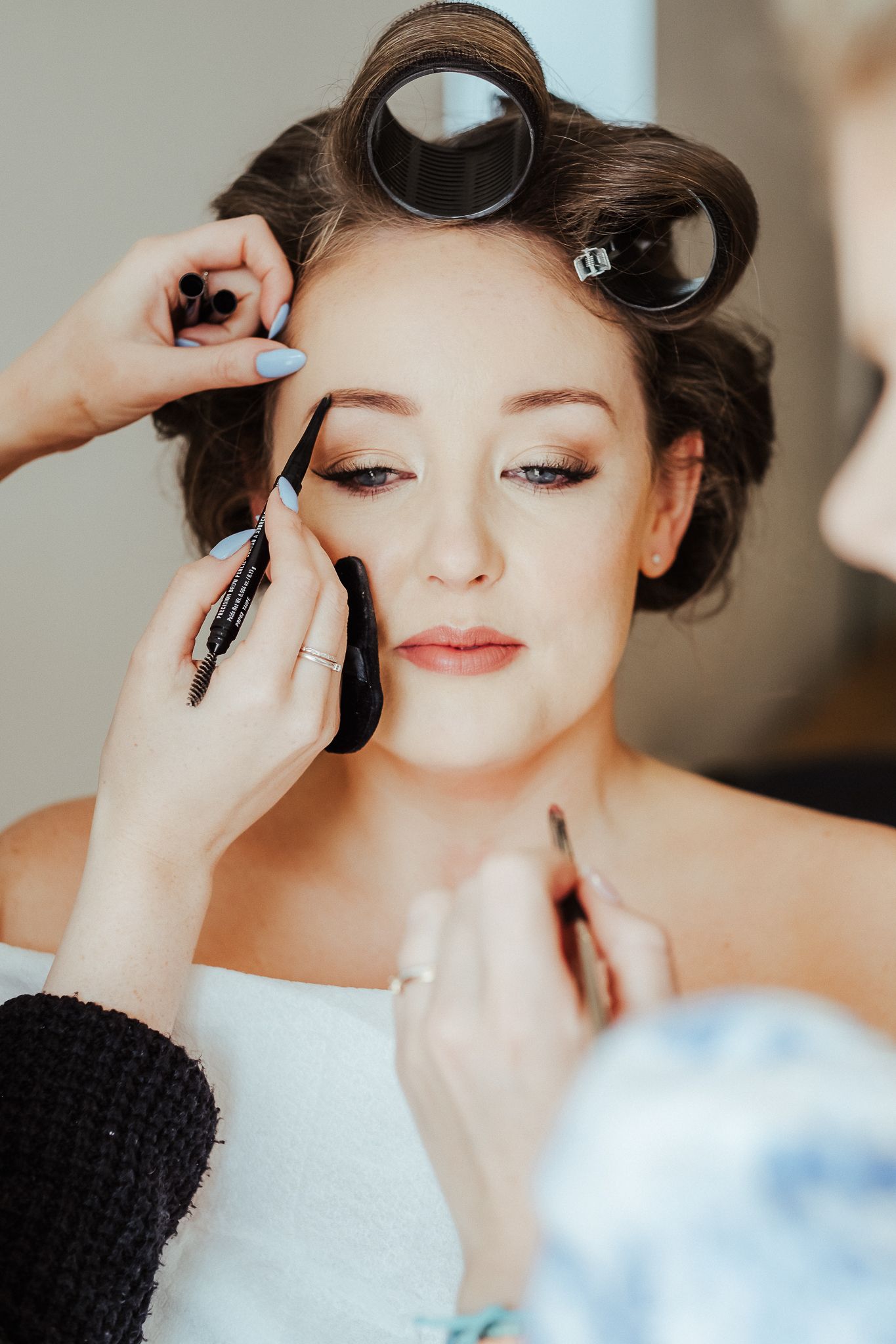Professional makeup application and styling for a special occasion with hair rollers.