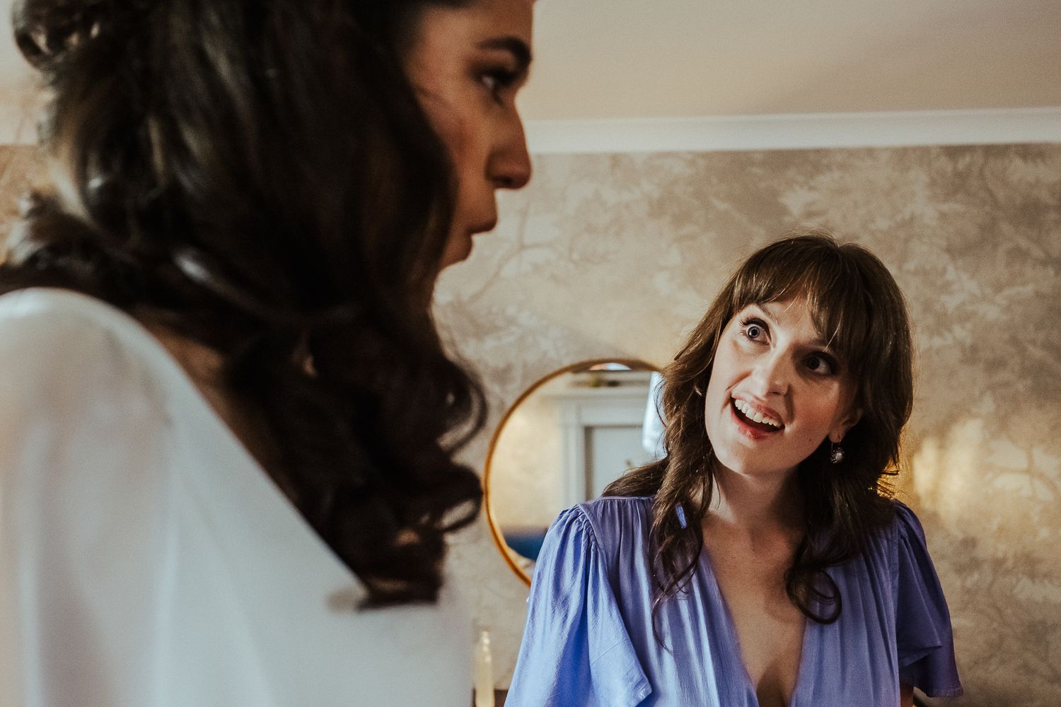 Two women share a joyful moment with excited expressions at a wedding event.