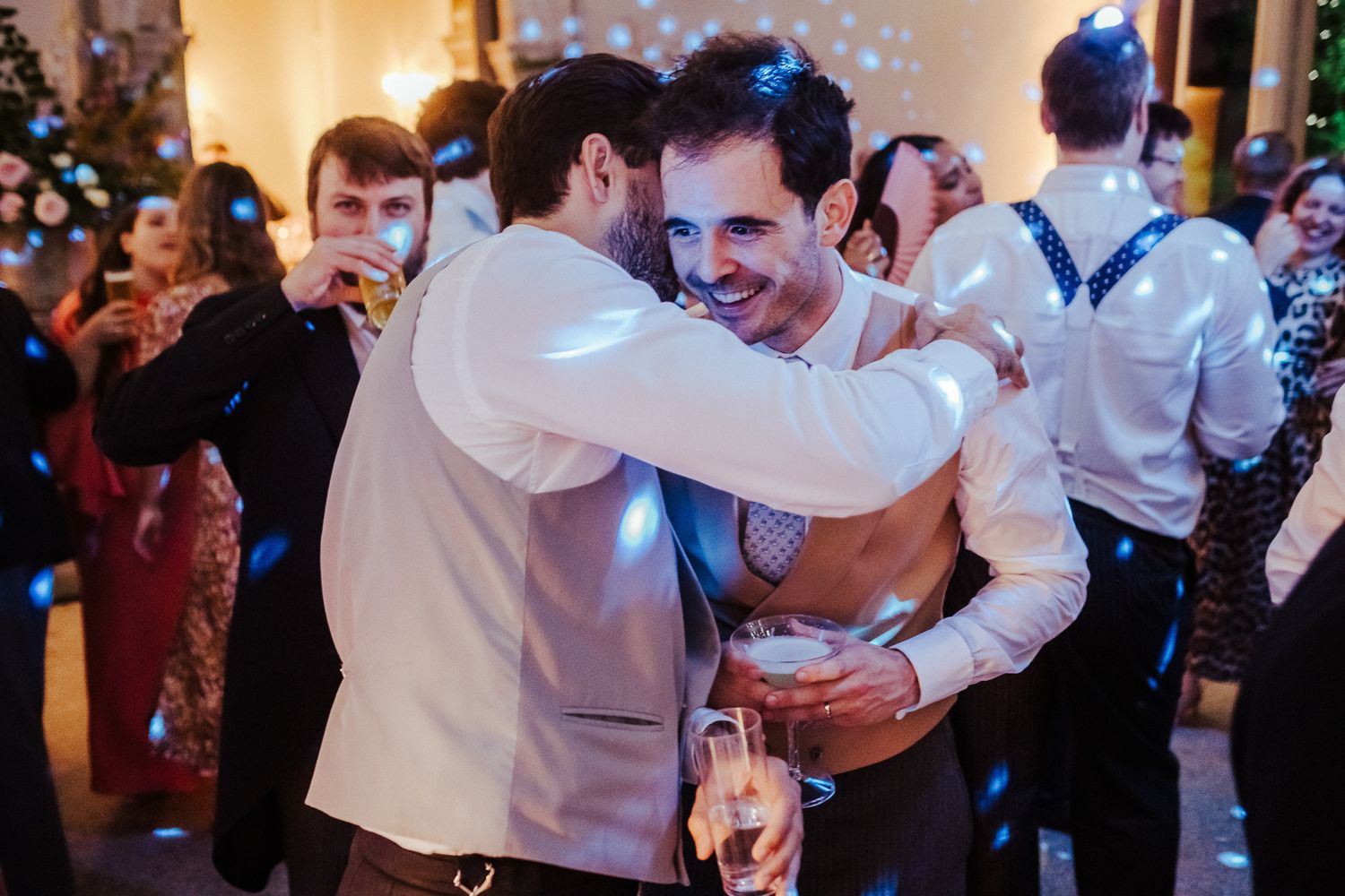 Two guests sharing a celebratory embrace on a festively lit dance floor.