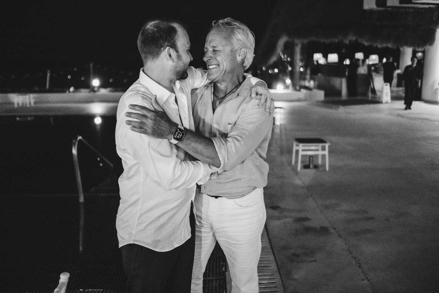 Two party guests share an intimate embrace while dancing at a nighttime celebration.