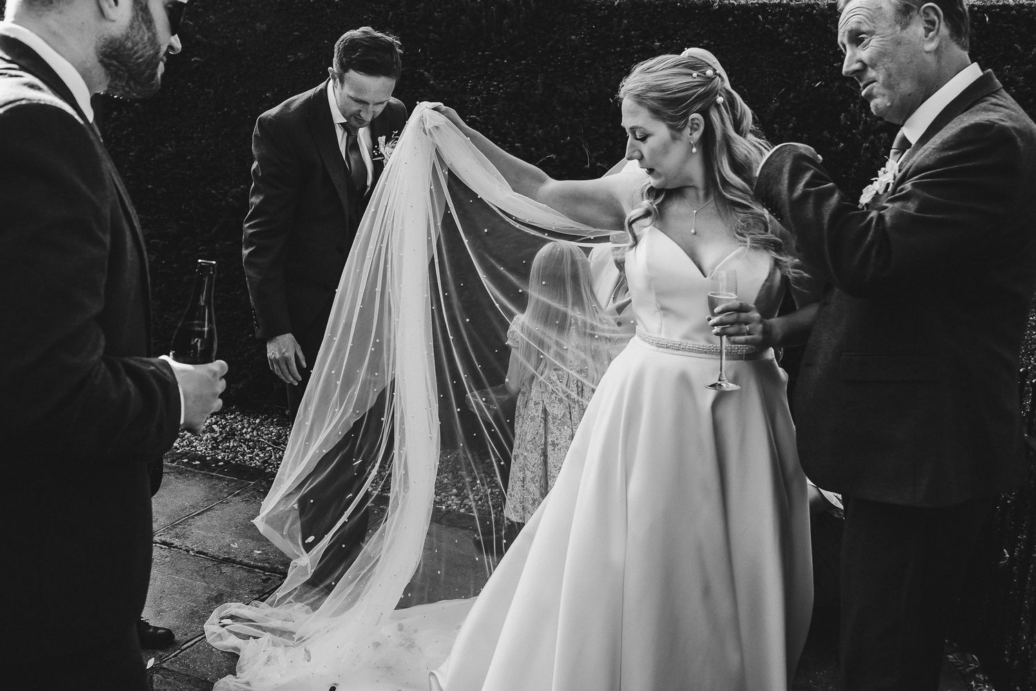 Wedding party members share embraces and conversations during outdoor celebration.
