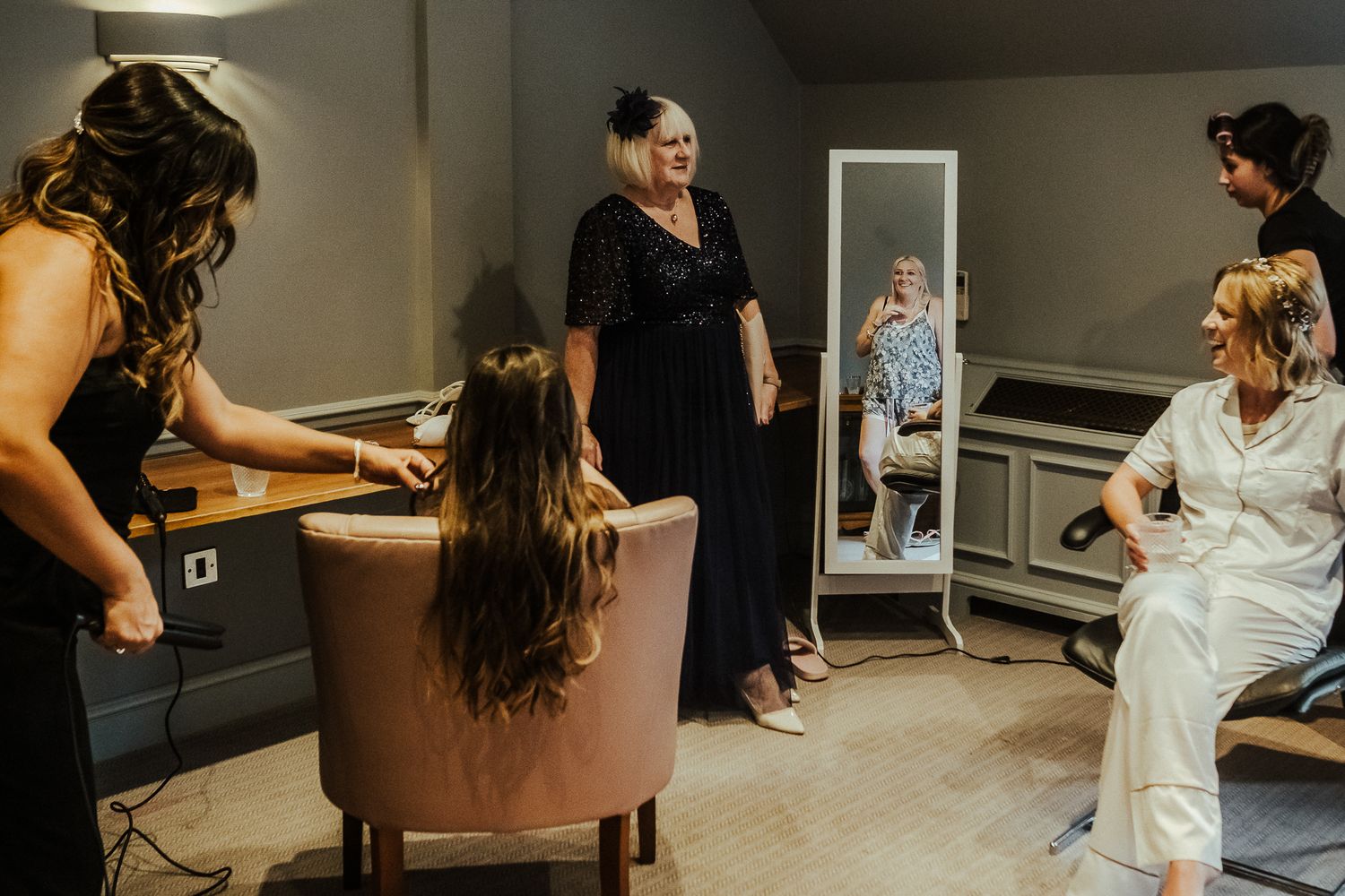Wedding preparation scene in a dressing room with attendees getting ready.
