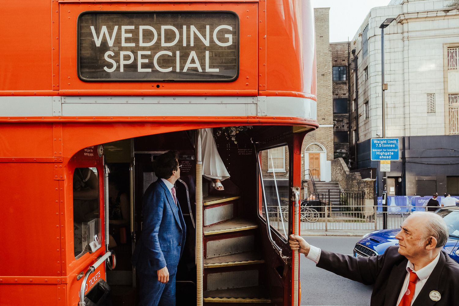 Red double decker bus with 'Wedding Special' sign and passengers boarding.