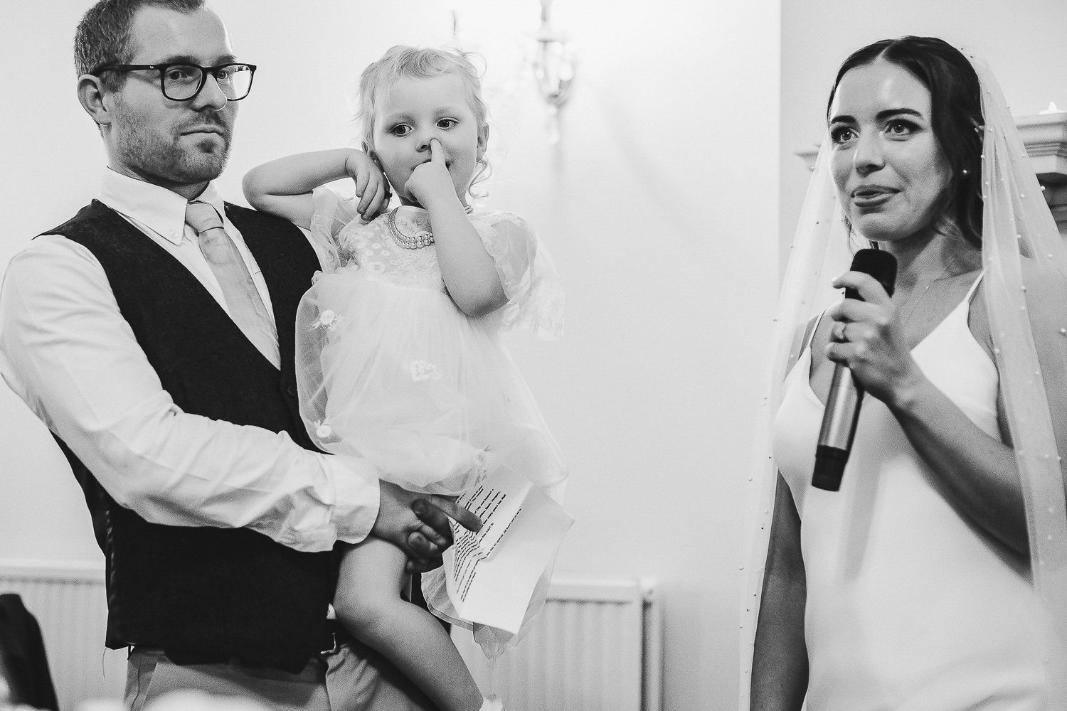 Wedding reception candid moment with speakers and emotional expressions.