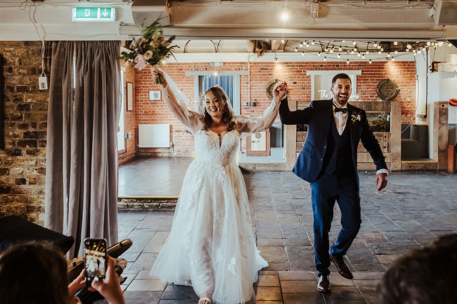 Happy newlyweds dancing and celebrating together in rustic indoor venue.