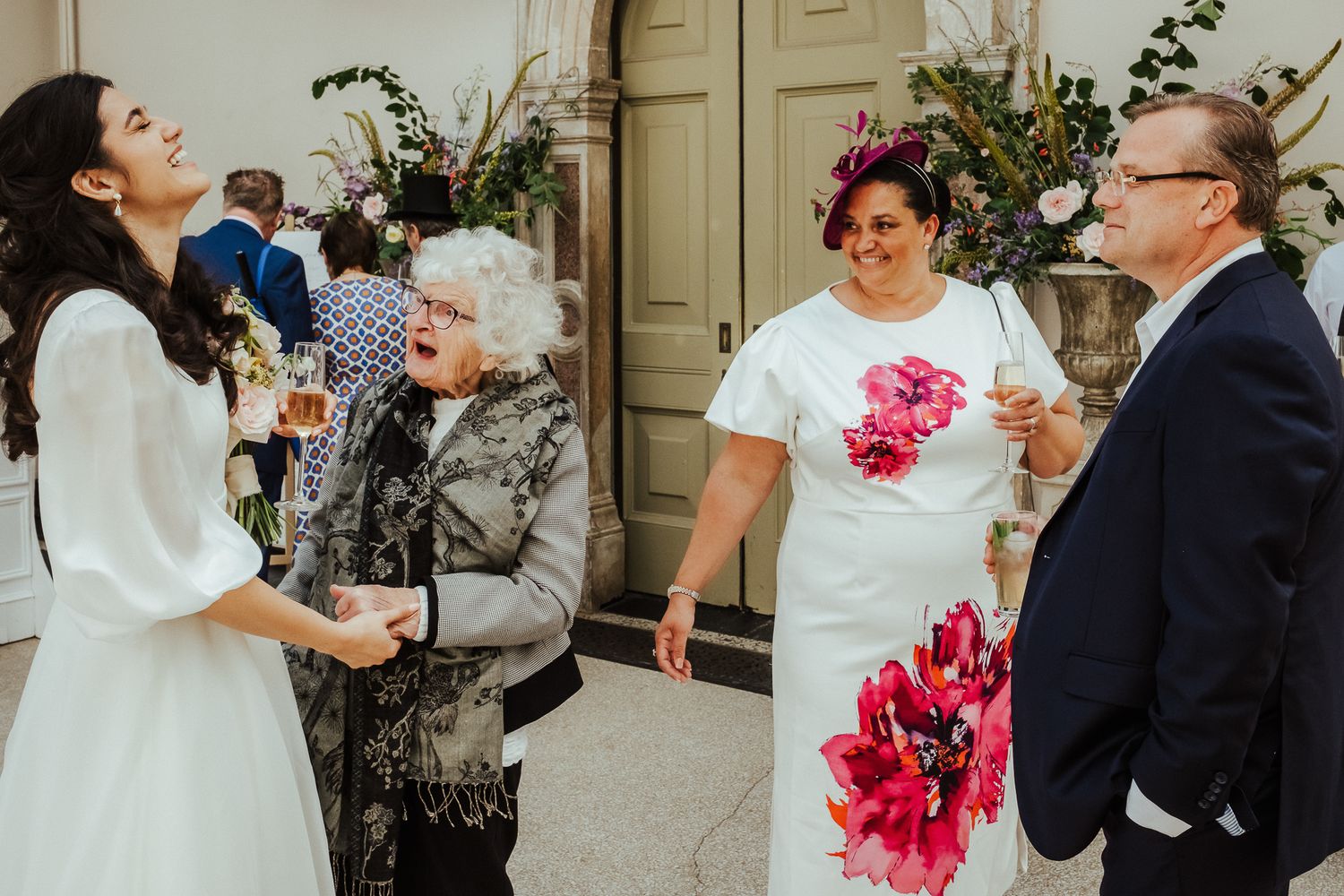 Wedding guests and couple enjoying drinks and conversation at an elegant indoor venue.