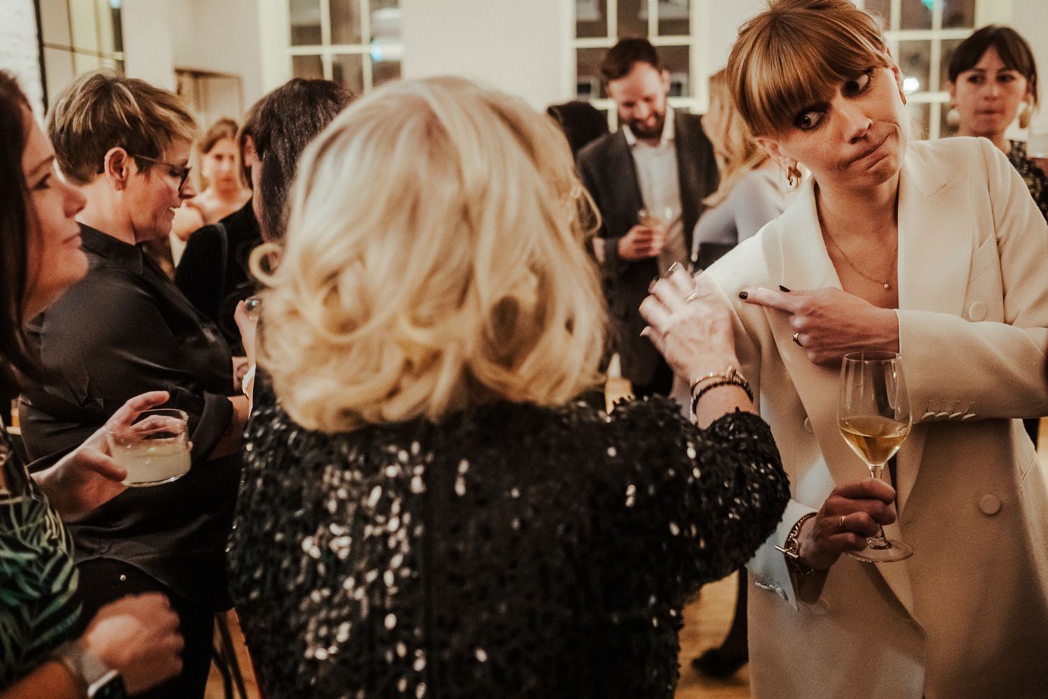 People mingling and chatting at an indoor social event with drinks.