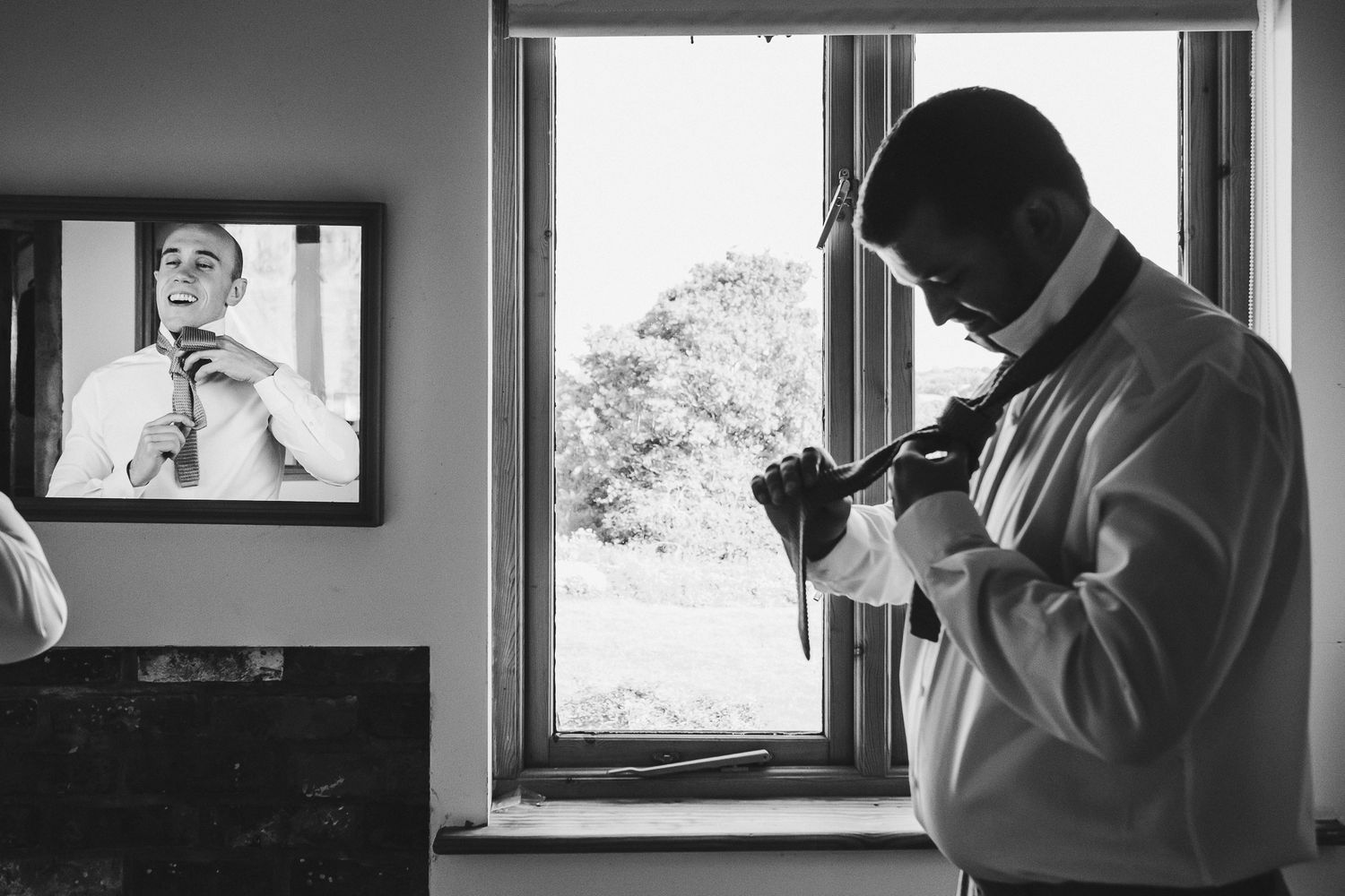 Man adjusting tie while looking at reflection in mirror.