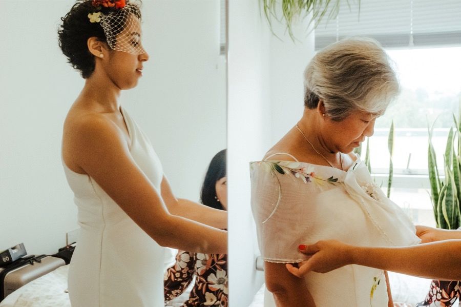 Bride getting dressed with help from others in a bright, modern room with houseplants.