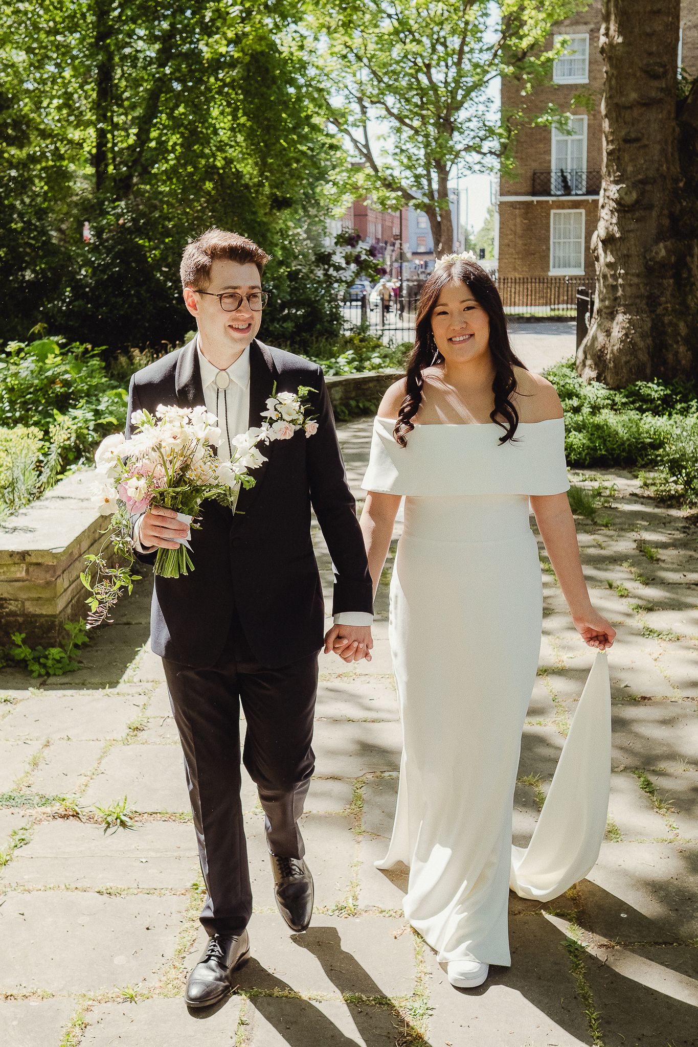 A series of five photos showing a couple walking together outdoors on a sunny day through a tree-lined path.