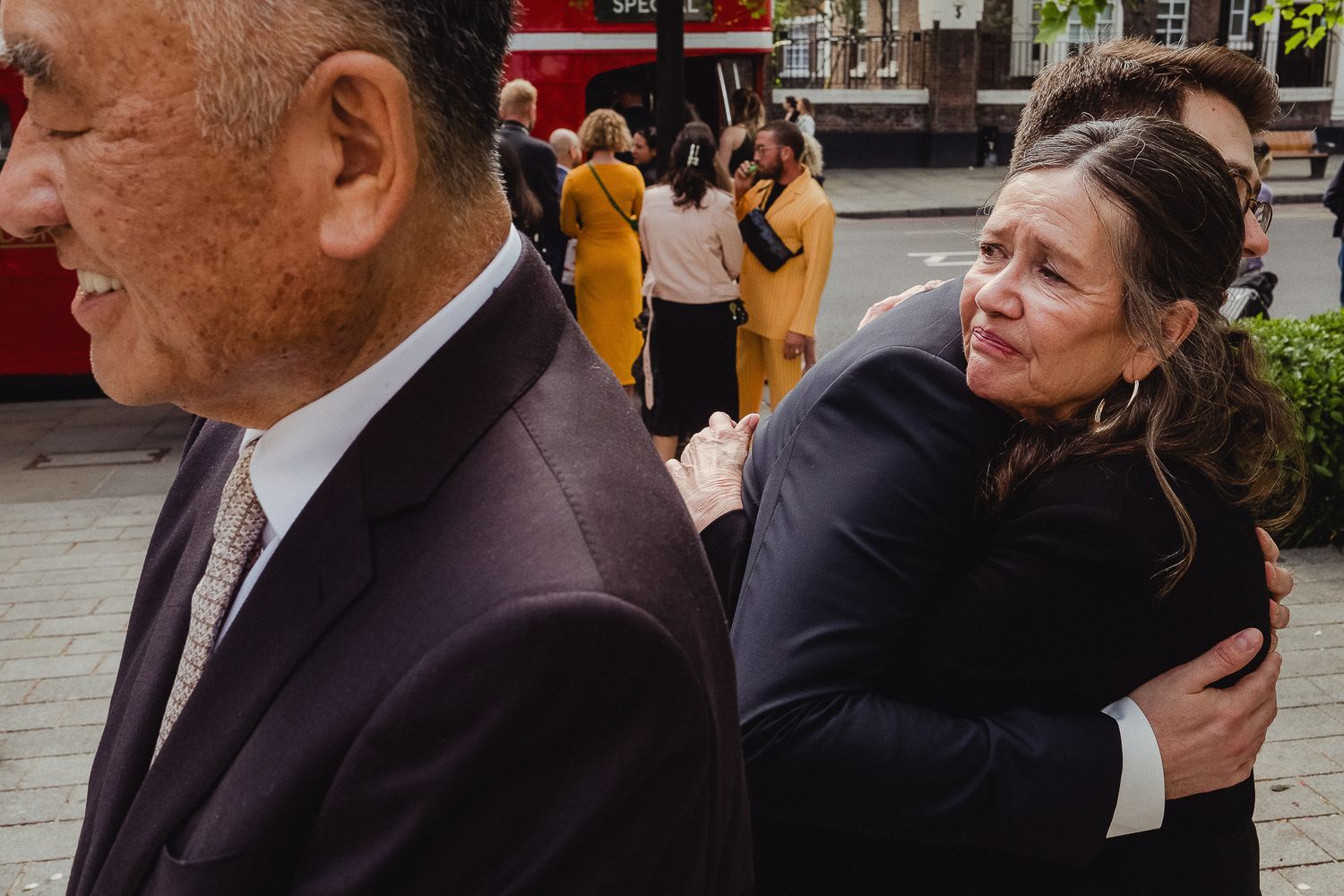 Two people on a city street, one in business attire and one in black casual wear, passing closely by each other.