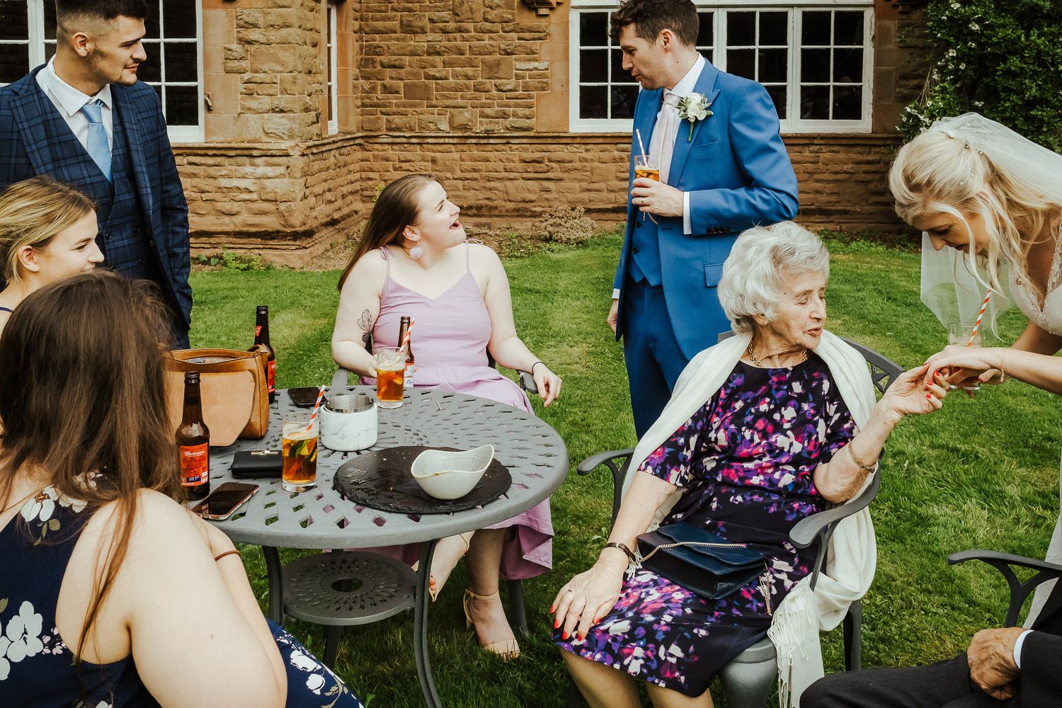 Wedding guests socialize and mingle in a garden setting.