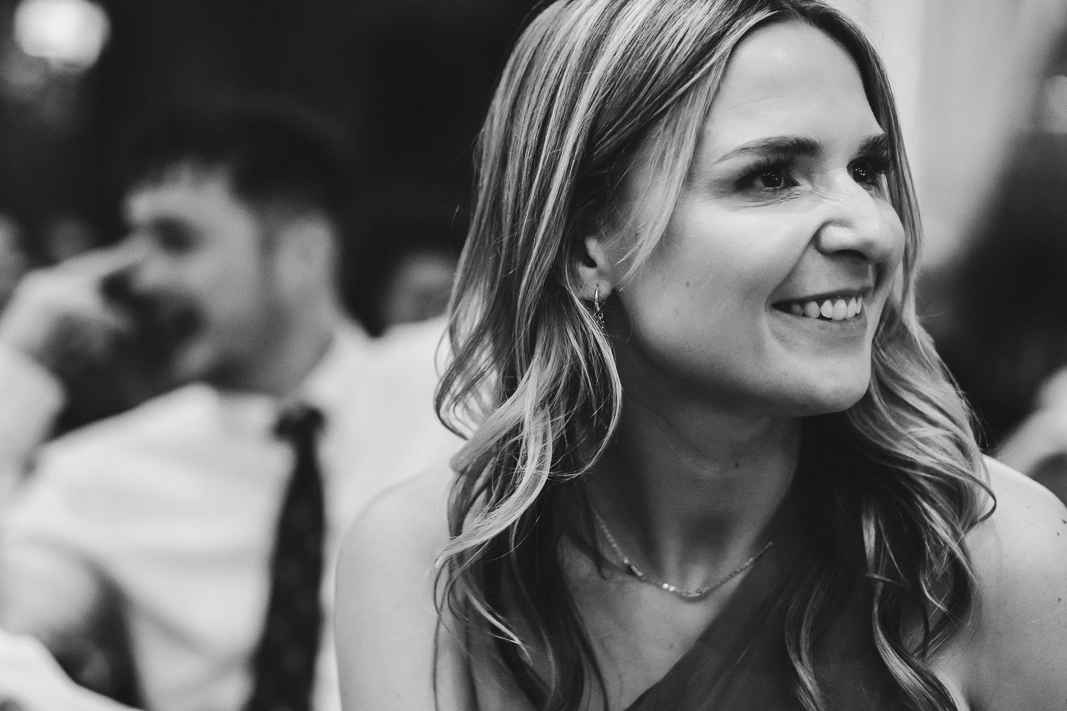 Black and white portrait of smiling guest during festive celebration.