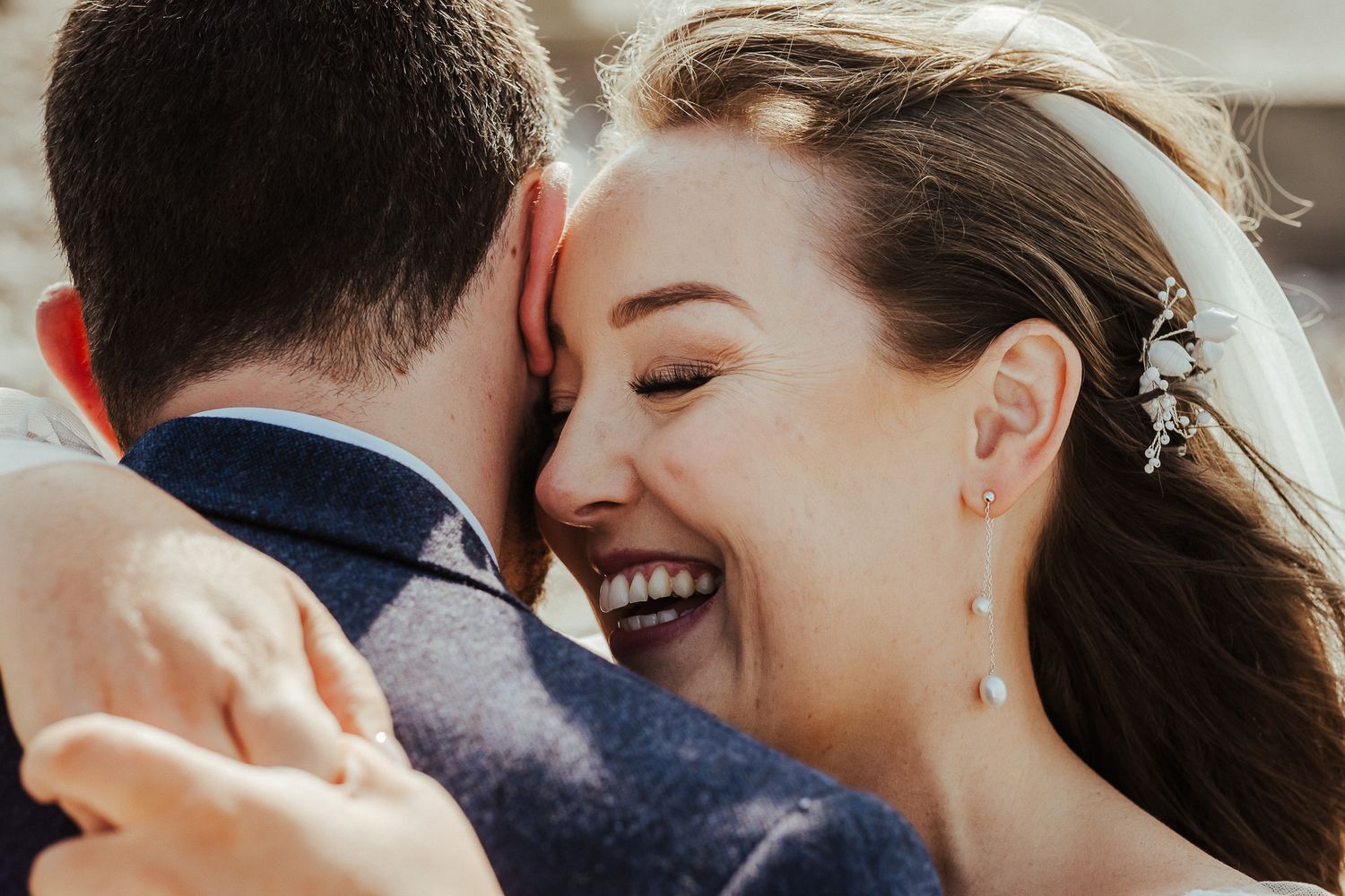Close up of joyful wedding couple embracing and laughing during intimate moment.