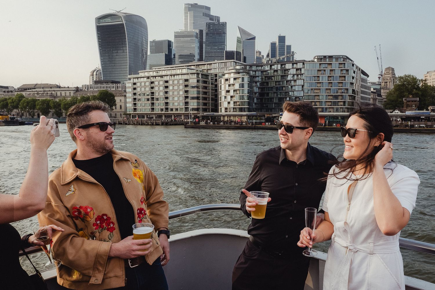 Private boat party cruising on calm waters with city skyline and tall buildings in the background.