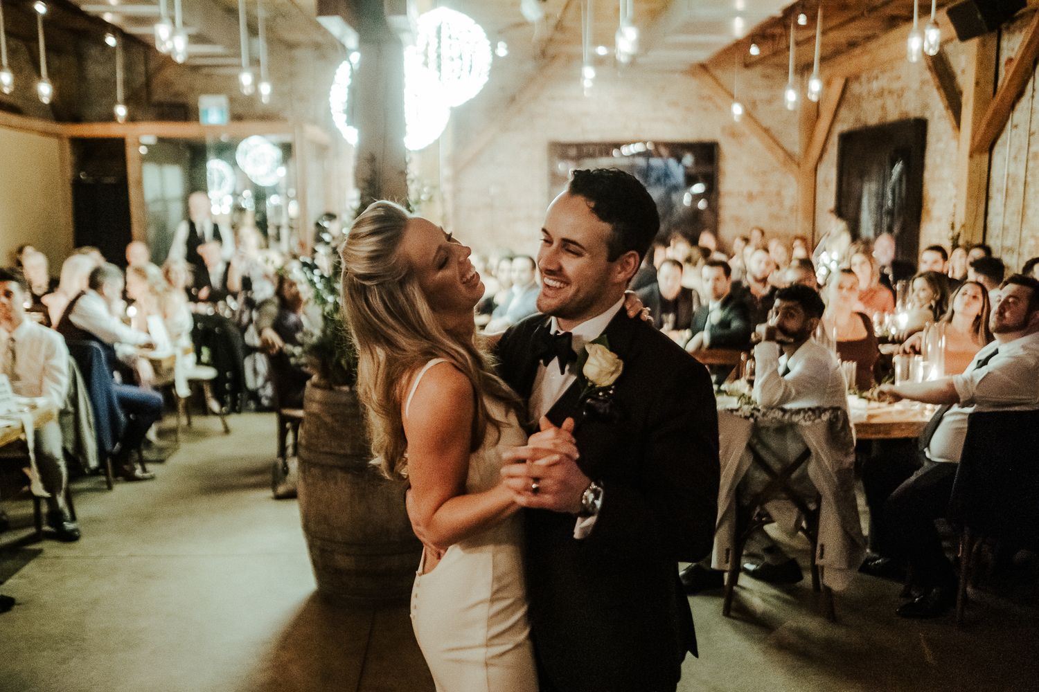 Wedding reception venue with warm lighting and rustic wooden beams.