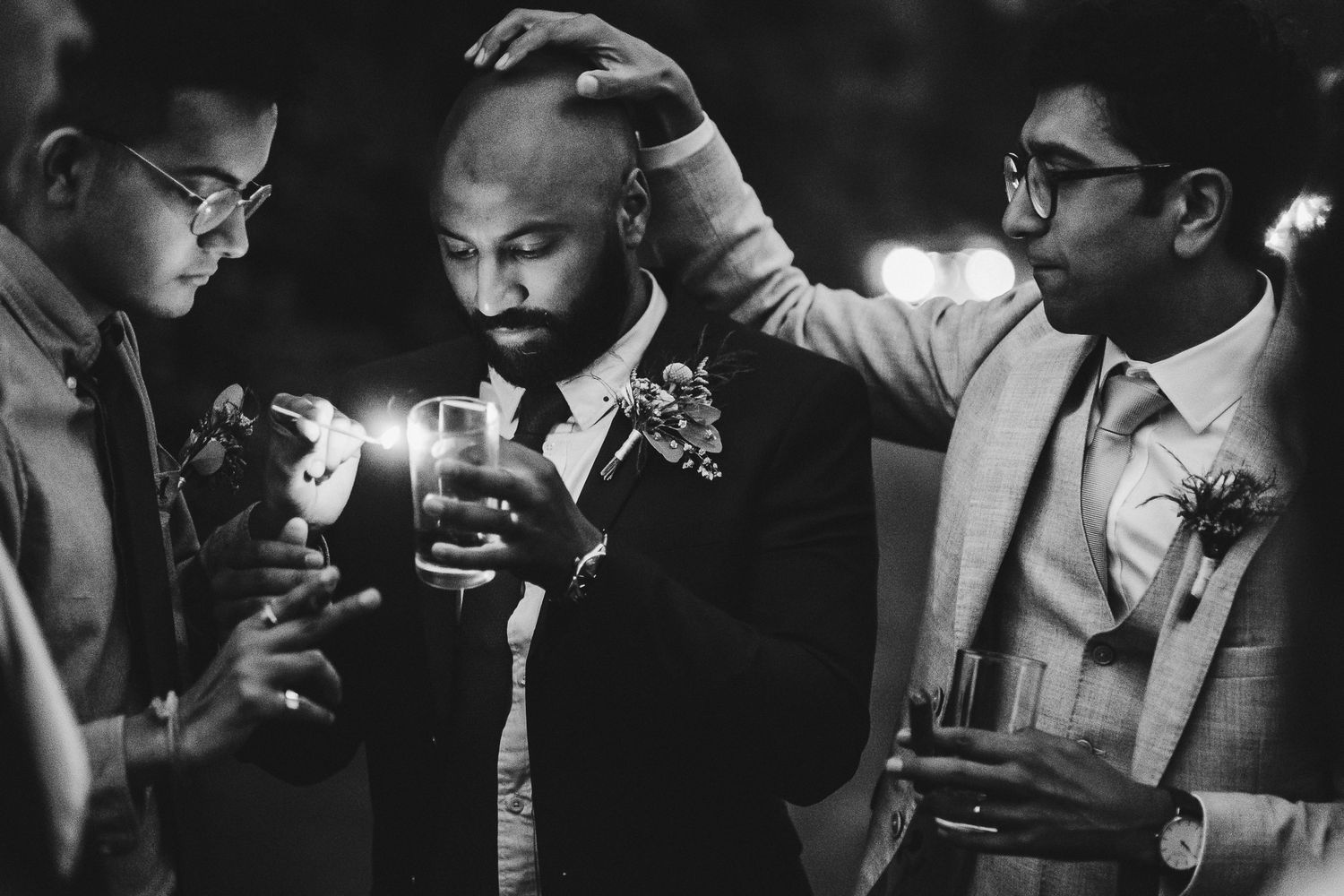 Three men in formal attire sharing drinks and conversation at an evening event.