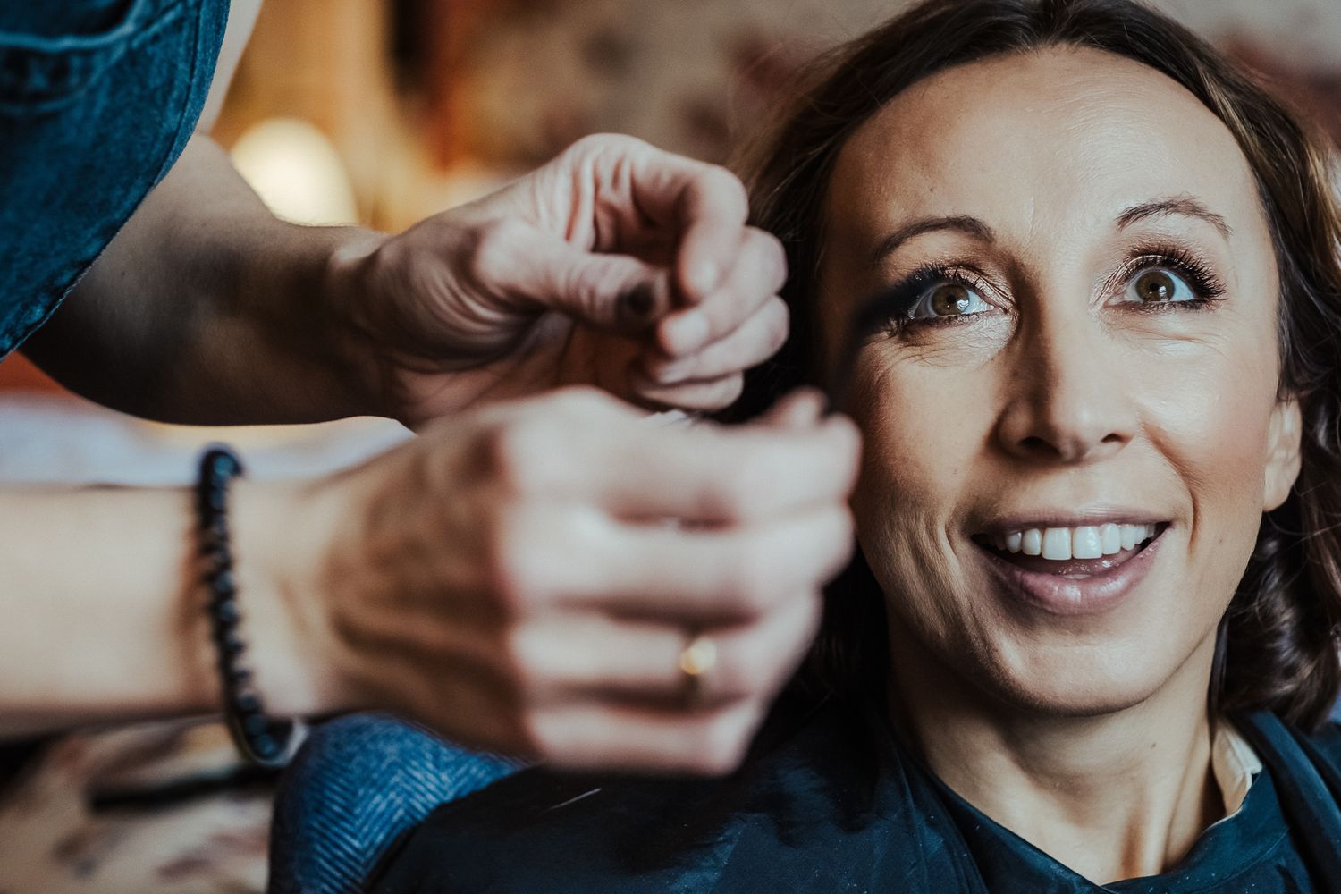 Close-up shot of someone having their hair styled while smiling with eyes looking upward.