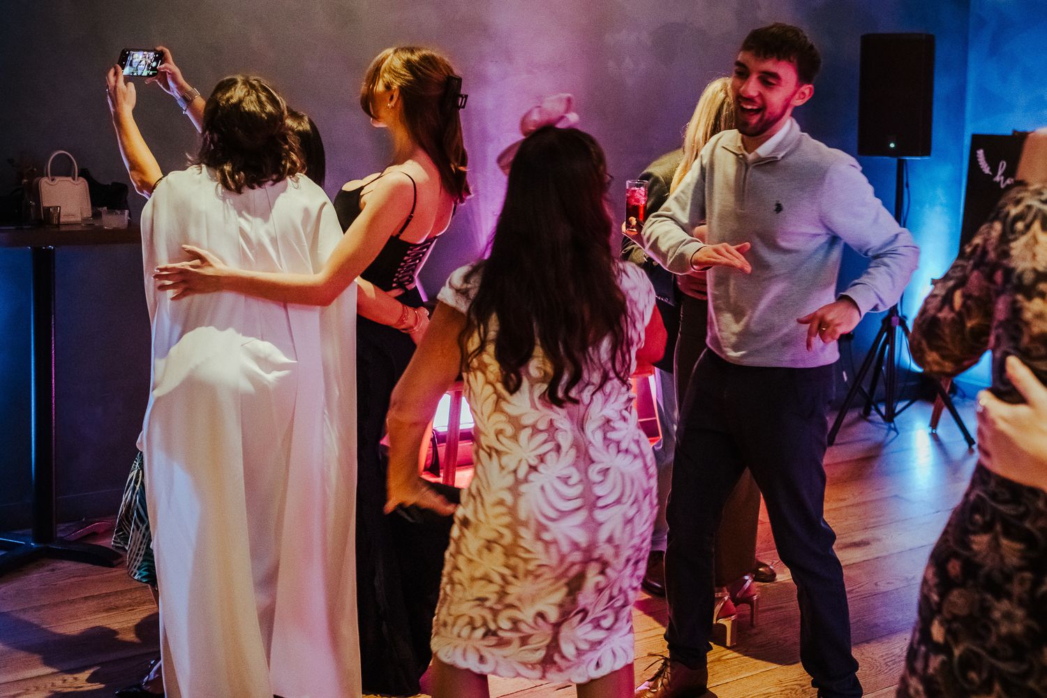 Wedding reception dance floor filled with guests celebrating under colorful lighting effects.