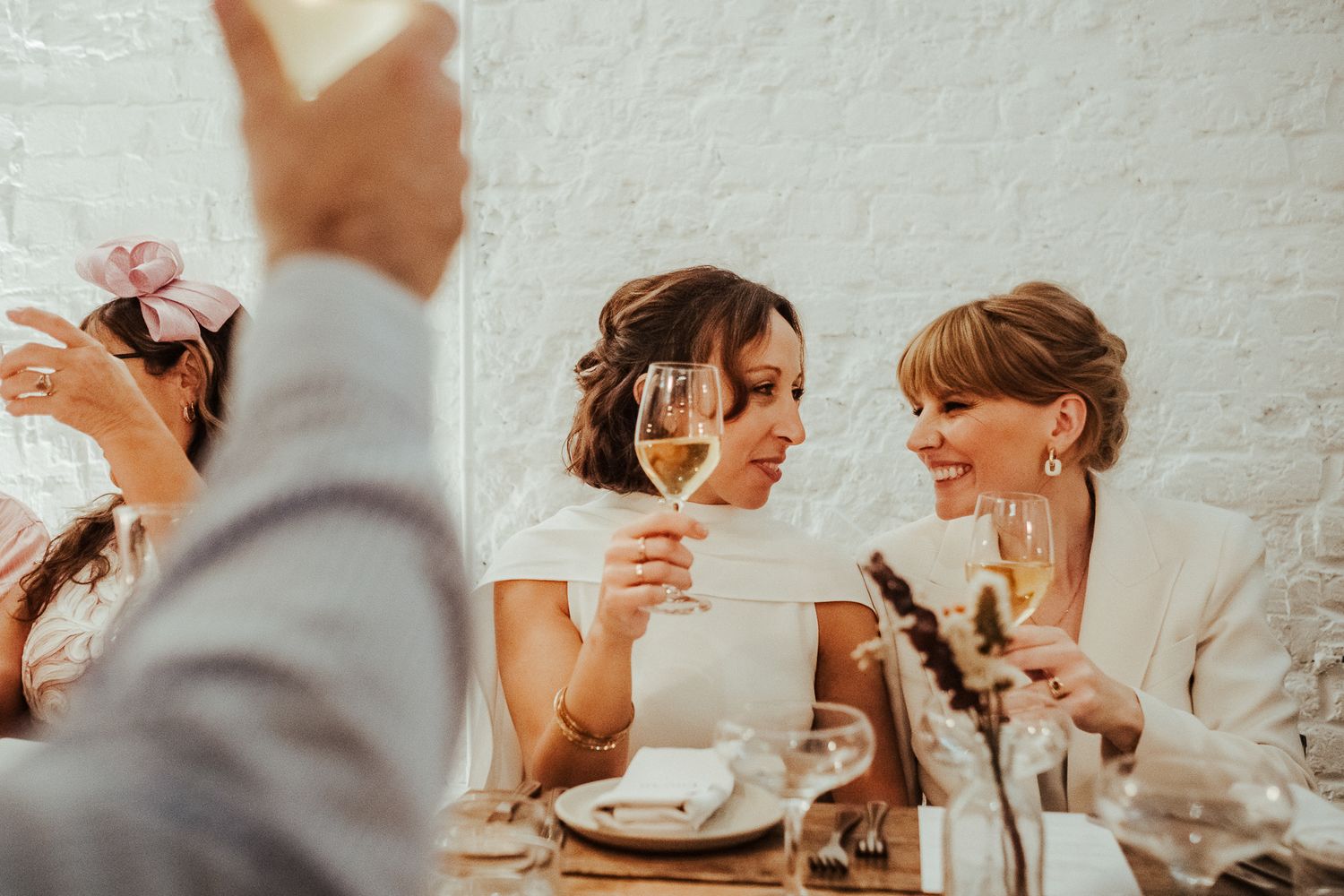Two people share drinks and laughter during an intimate wedding reception.