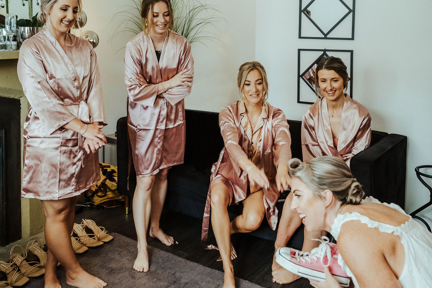 Group wearing matching pink robes gather during pre-wedding preparations.