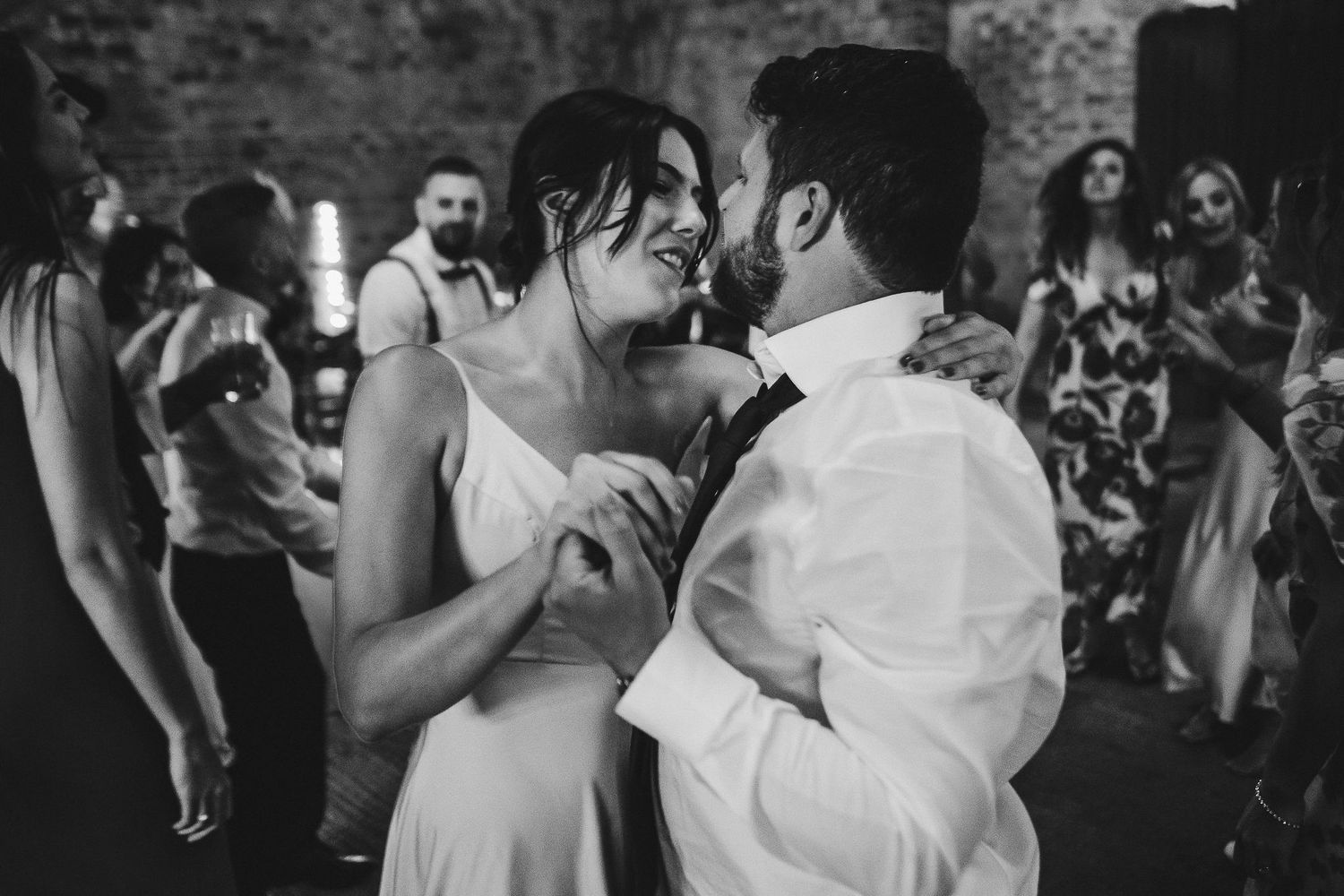 Couple sharing an intimate dance moment at a dimly lit wedding reception.