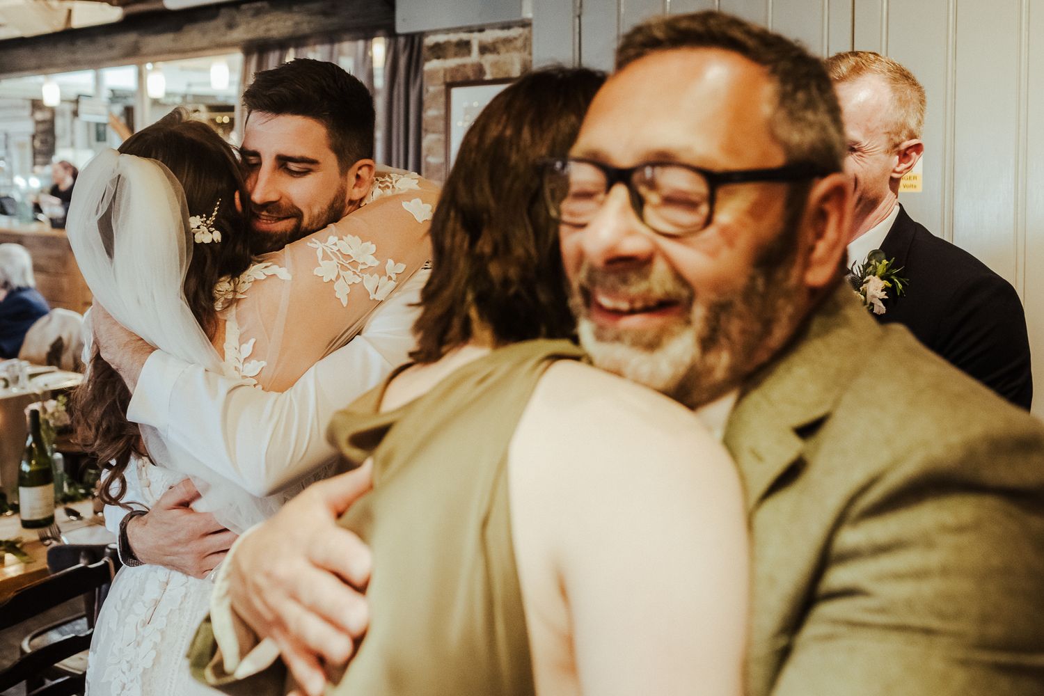 Candid reception photo showing warm embraces and genuine smiles among wedding guests.