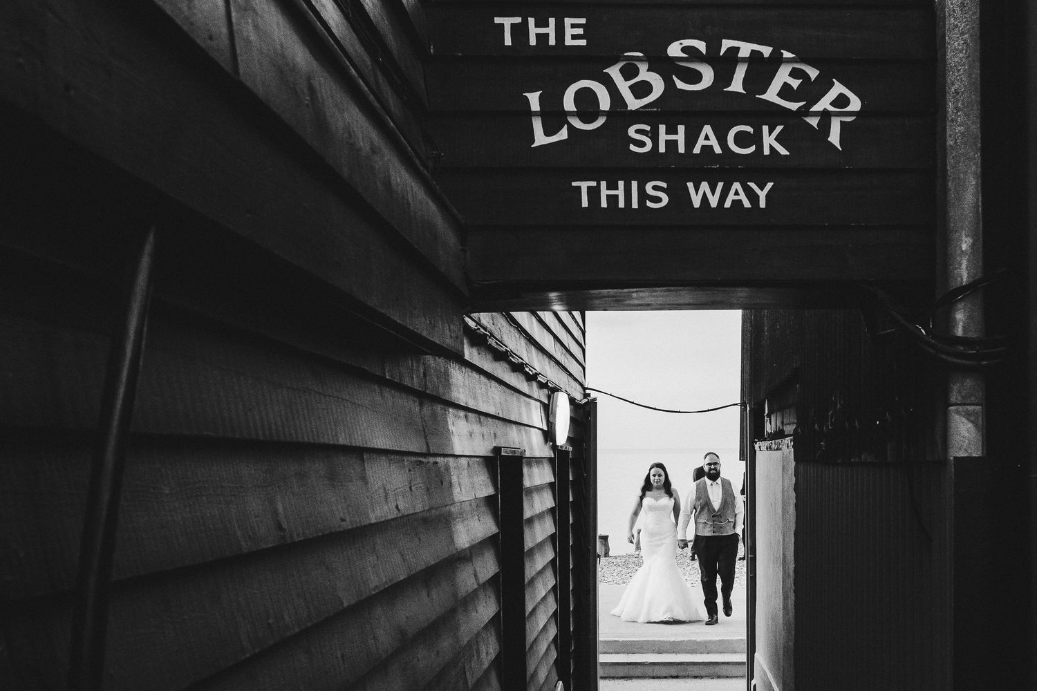 A moody black and white corridor leading to The Lobster Shack with silhouettes walking in the distance.