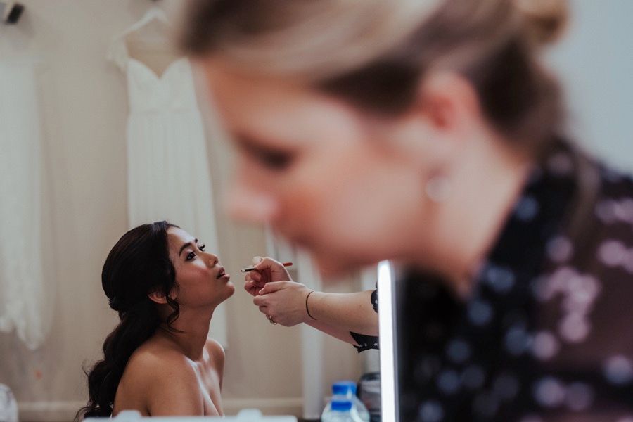 Wedding preparation scene with makeup application in soft natural lighting.
