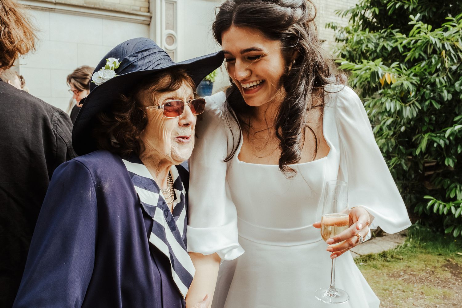 Wedding guests sharing drinks and laughter at an outdoor celebration.