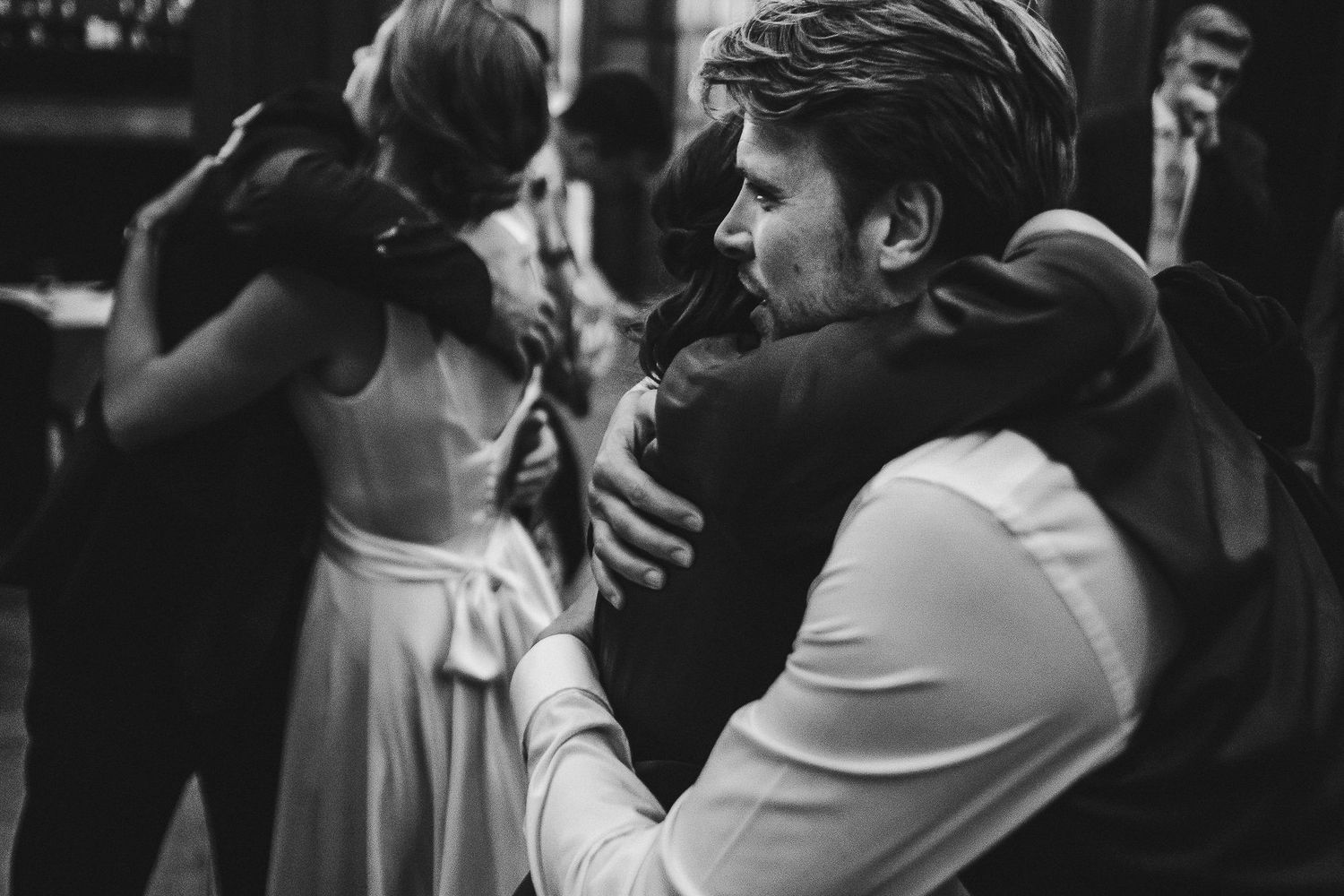 Black and white photo of couples slow dancing at an intimate reception.