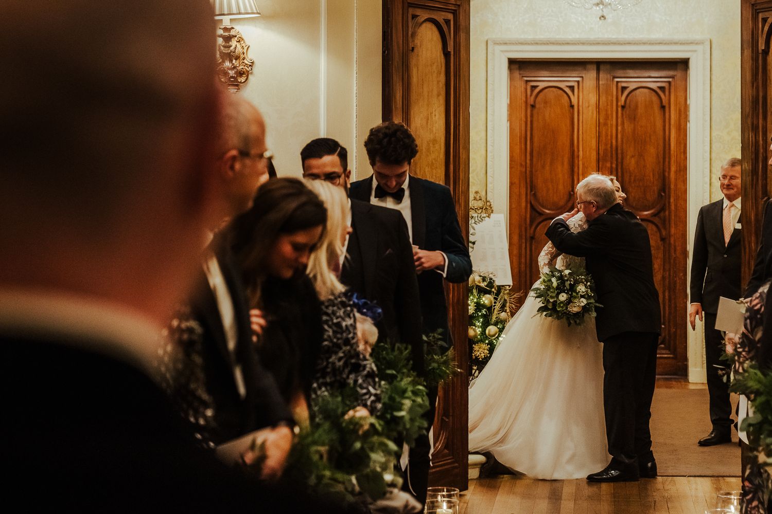 Elegant wedding ceremony in a historic venue with wooden doors and floral decorations.