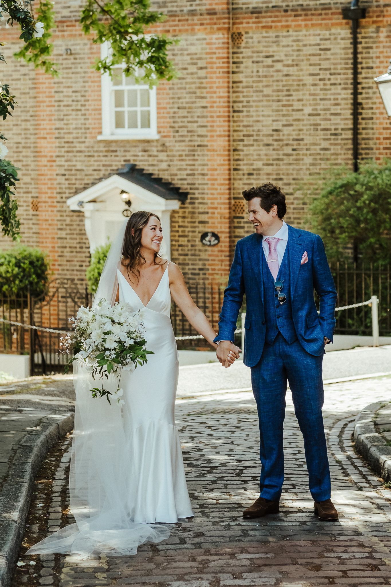 A romantic wedding portrait on a cobblestone street with brick architecture backdrop.