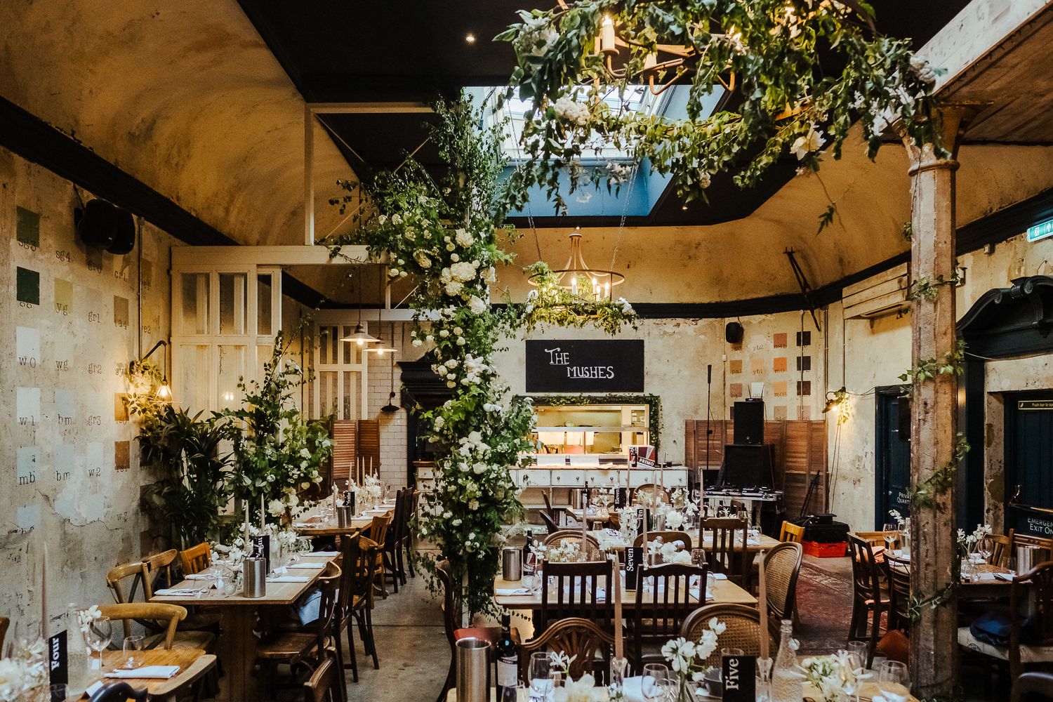 Rustic restaurant interior decorated with hanging plants and wooden furniture for a wedding reception.