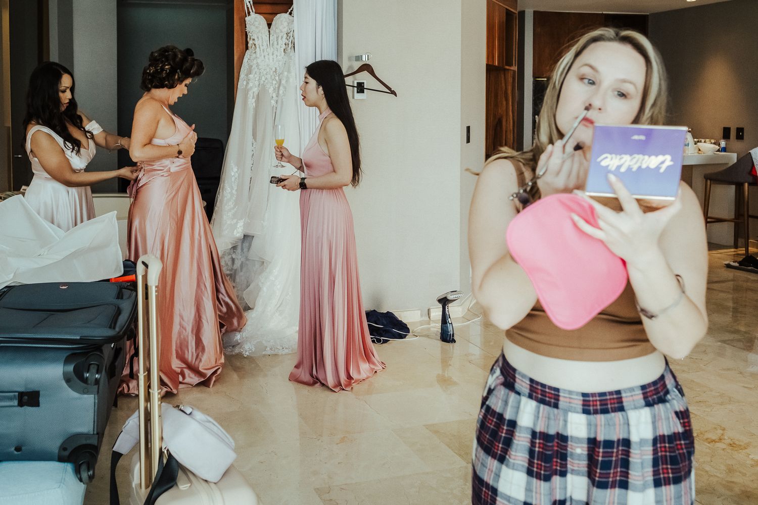 Wedding preparation scene with bridesmaids in pink dresses and casual attire.