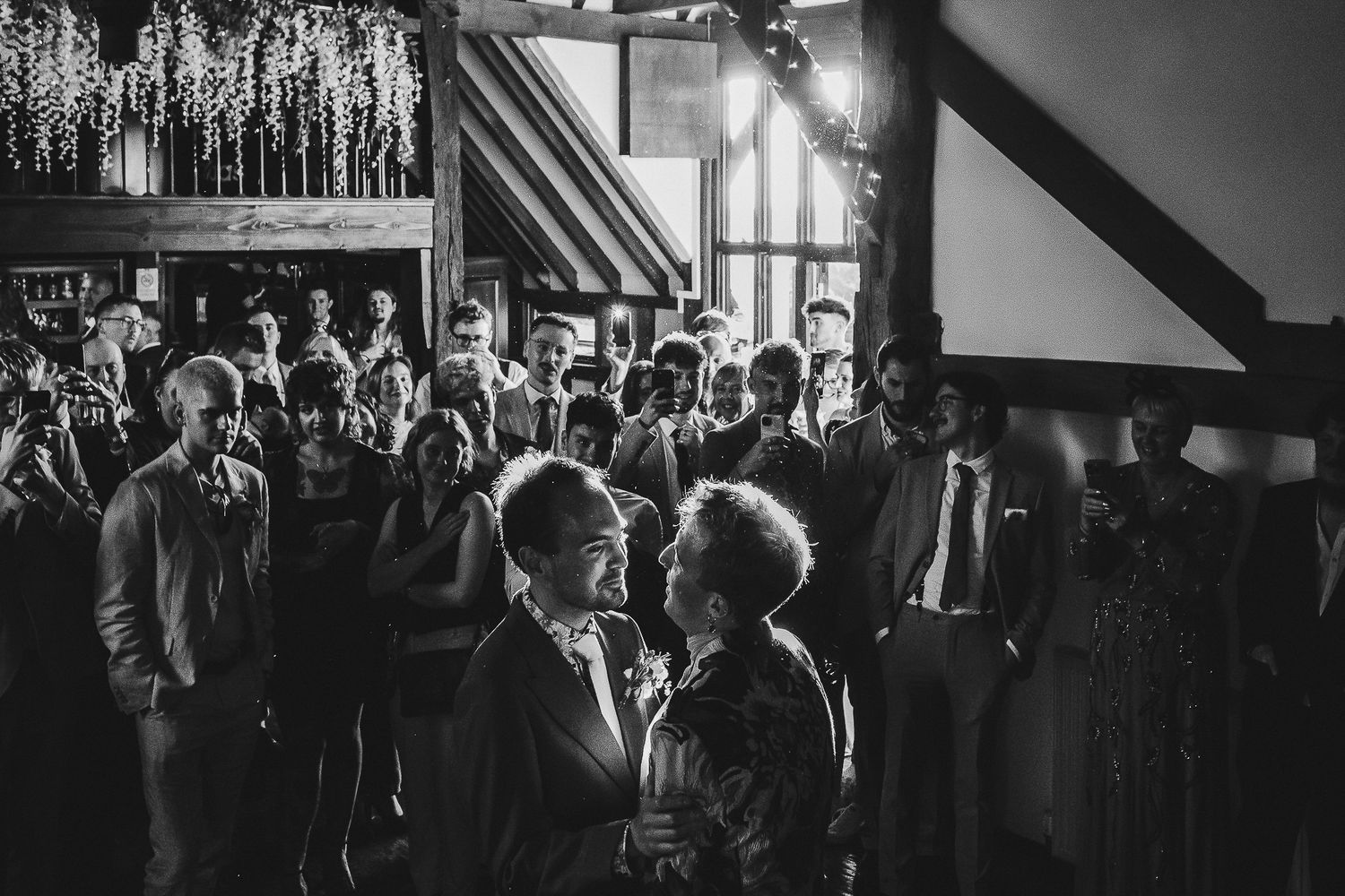 Black and white photo of couples dancing at an intimate indoor reception.