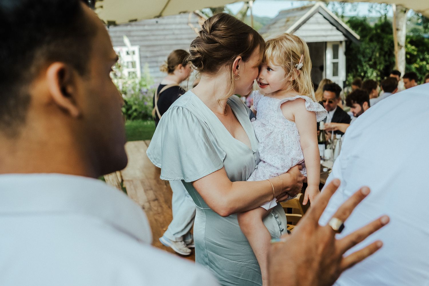 Candid outdoor reception moment with guests interacting during a summer wedding.