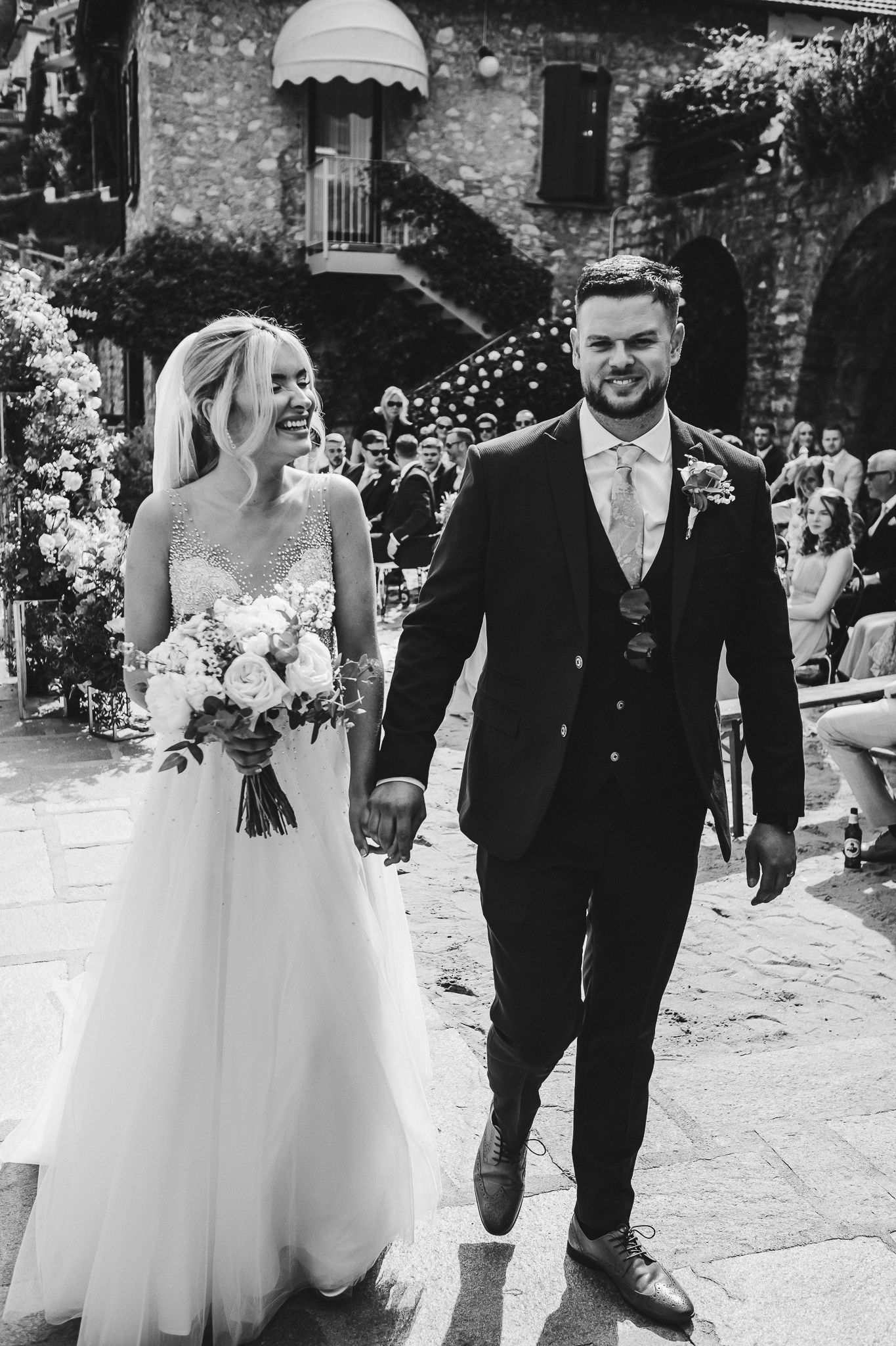 A joyful couple walking down stone steps after their wedding ceremony.