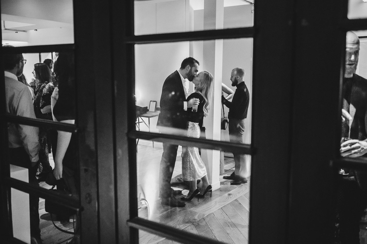 Black and white photo of people conversing through window panes at an indoor venue.