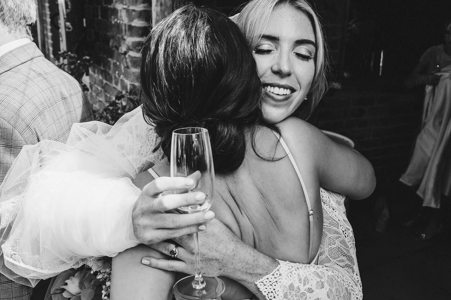Black and white photo of a celebratory moment with wine glasses at a wedding reception.