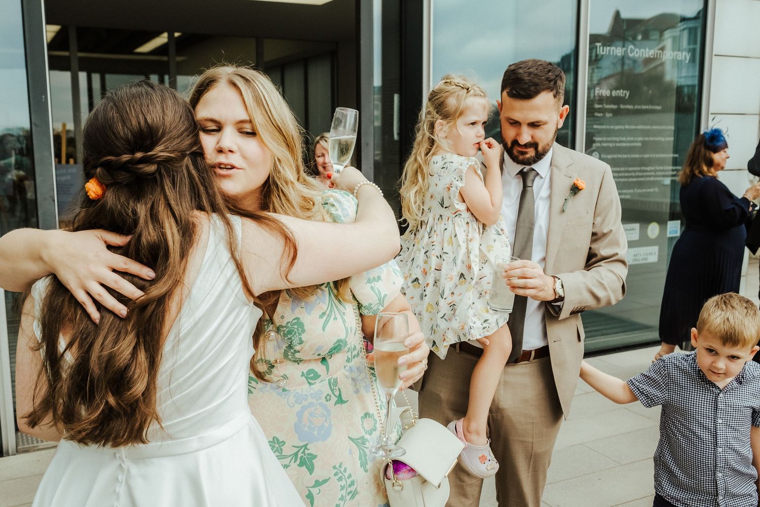 Guests celebrate with warm embraces at an outdoor wedding gathering.