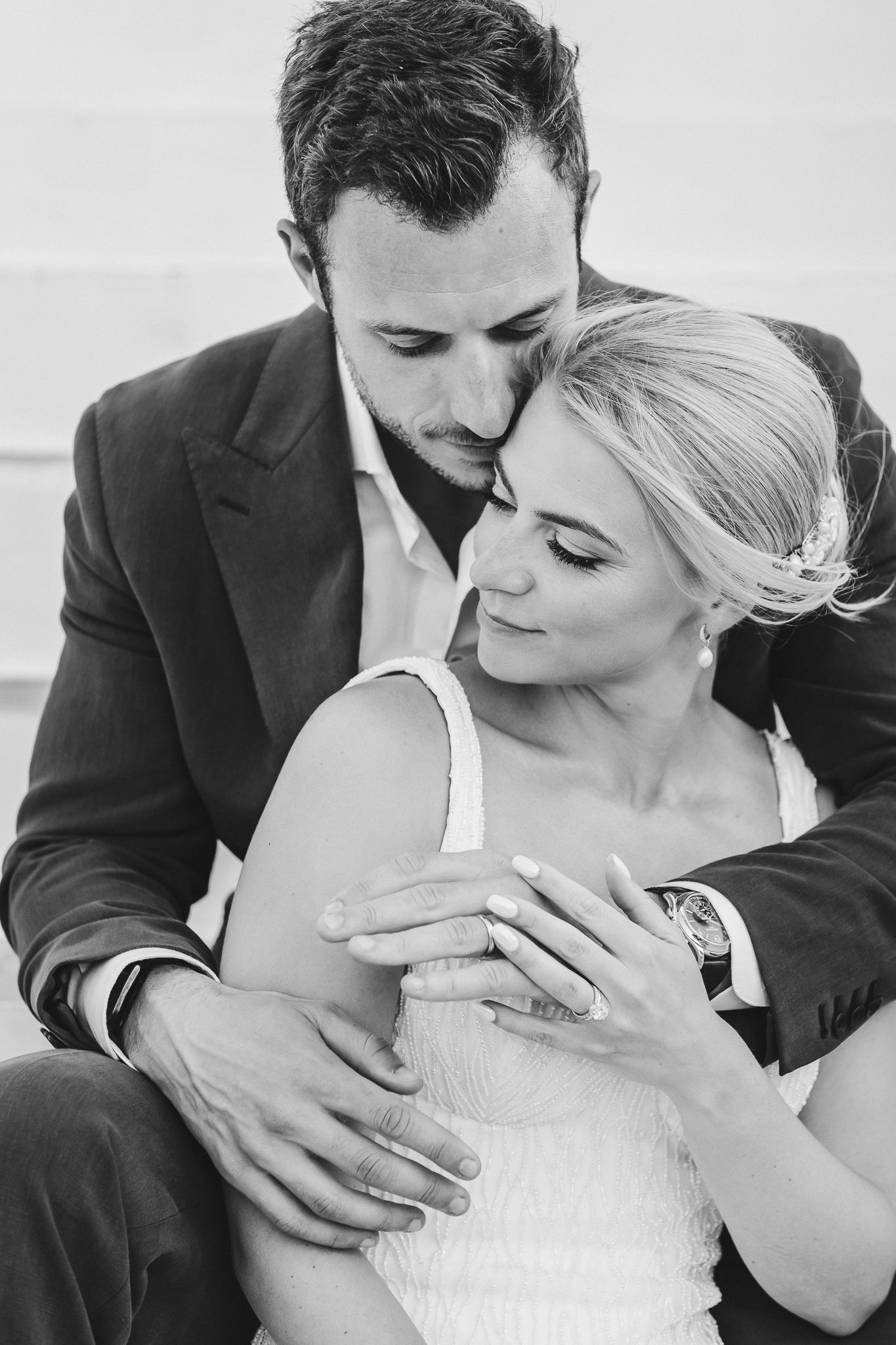 Intimate black and white portrait of couple in formal attire sharing tender moment.